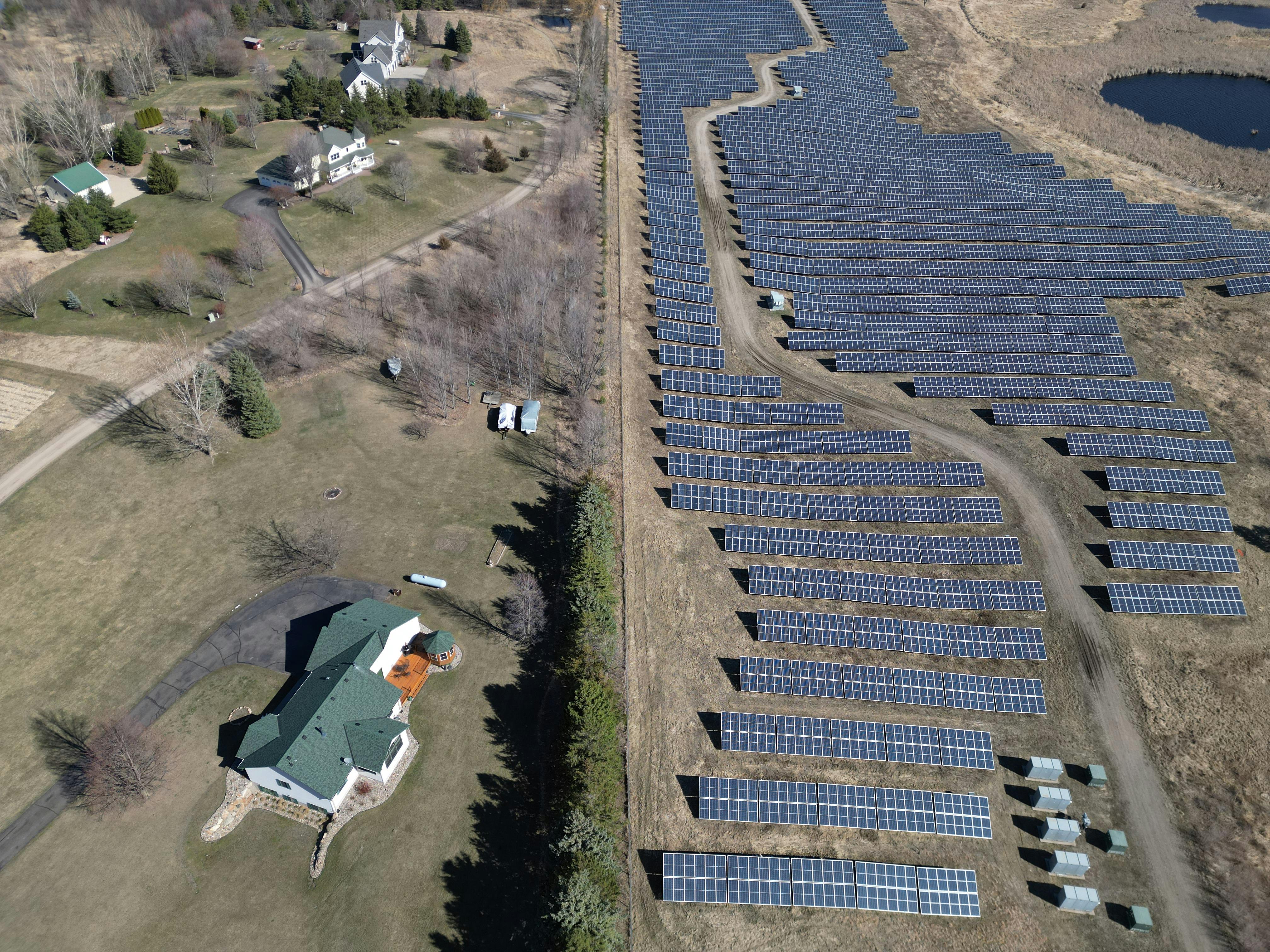 Aerial image showcasing a solar farm adjacent to a residential area in a rural setting.