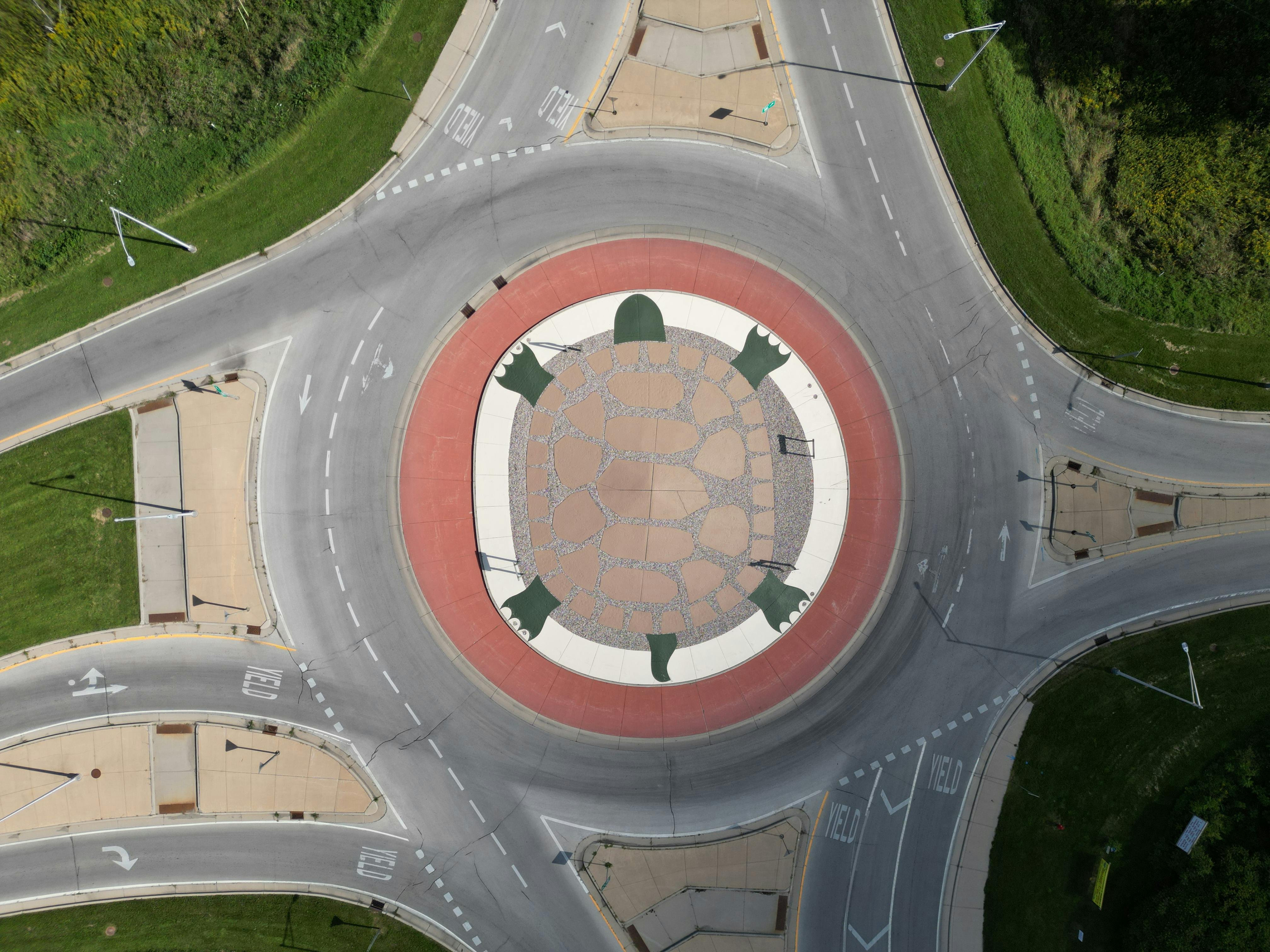 Aerial shot of a turtle design on a roundabout surrounded by roads and greenery.