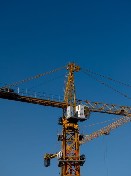Free Yellow construction crane set against a vibrant blue sky, showcasing industrial machinery. Stock Photo