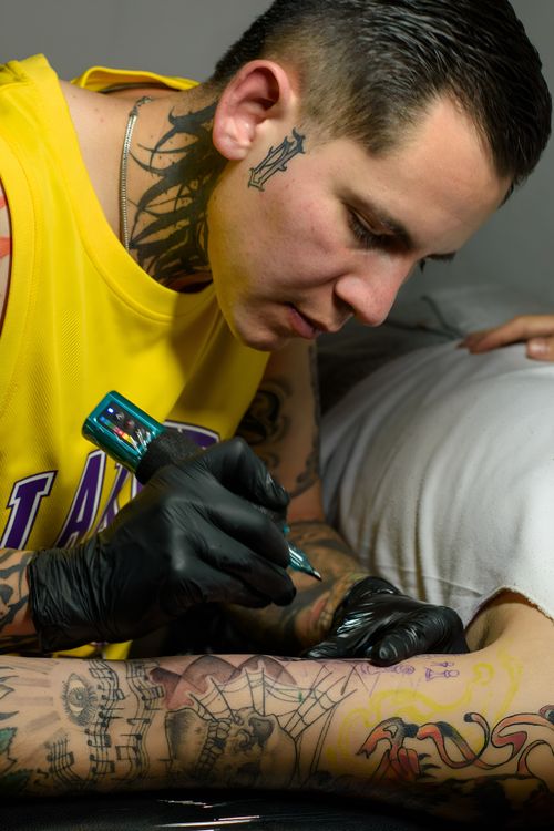 Free Tattoo artist working on a client's arm, showcasing intricate designs and vibrant colors. Stock Photo