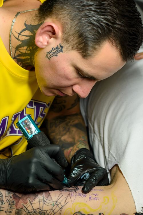 Free Tattoo artist engrossed in creating a detailed tattoo design in a studio setting. Stock Photo