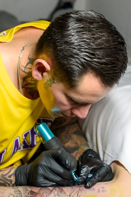 Free Close-up of a tattoo artist focused on creating a design in a studio. Stock Photo