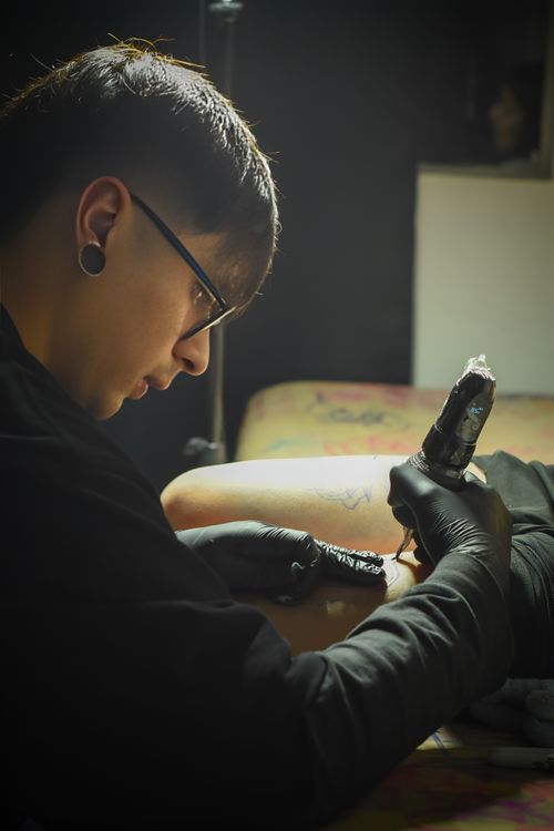Free A focused tattoo artist creating body art in a dimly lit studio. Stock Photo