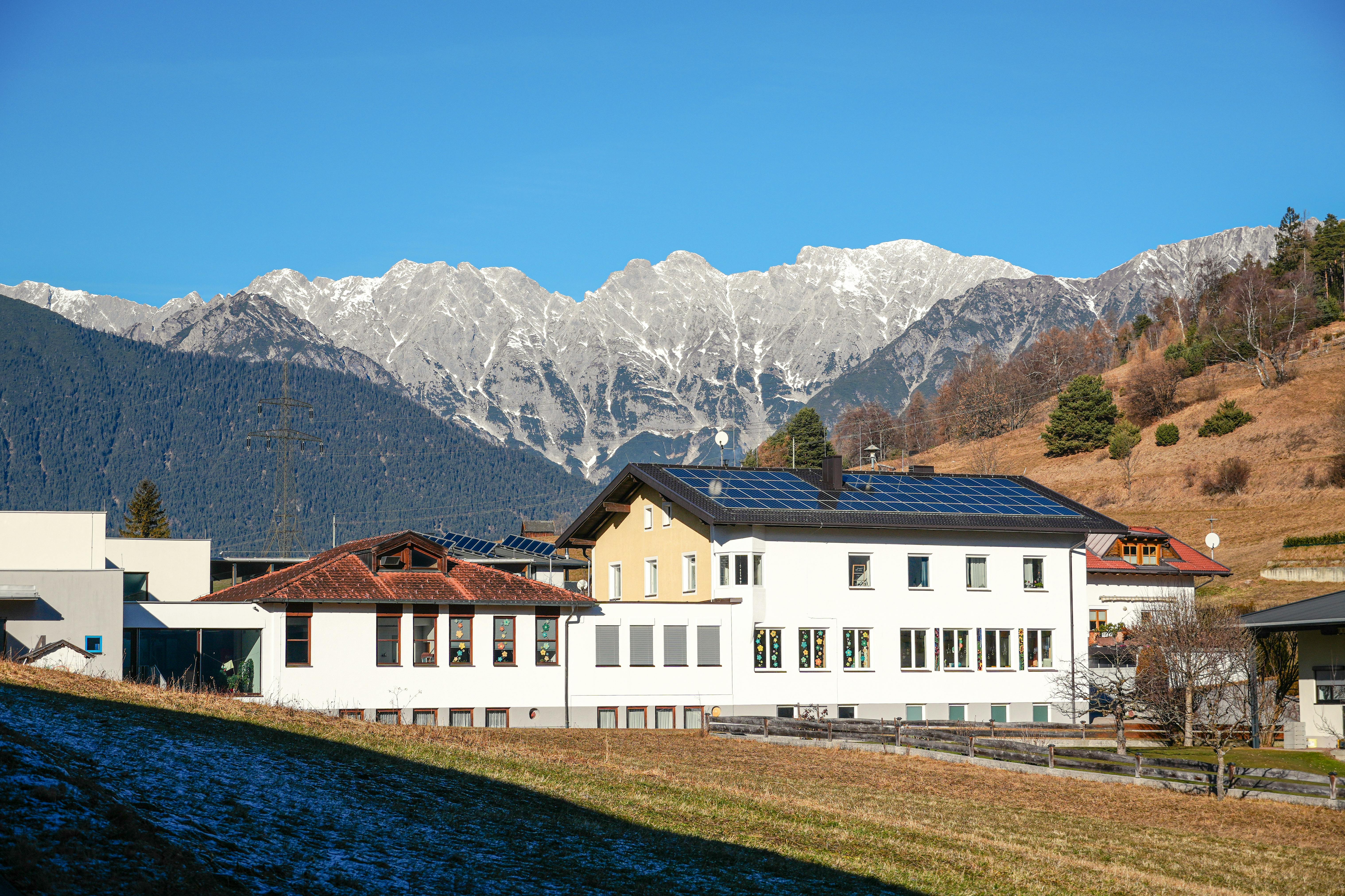 Un village serein aux toits solaires, avec les montagnes en toile de fond, au Tyrol.