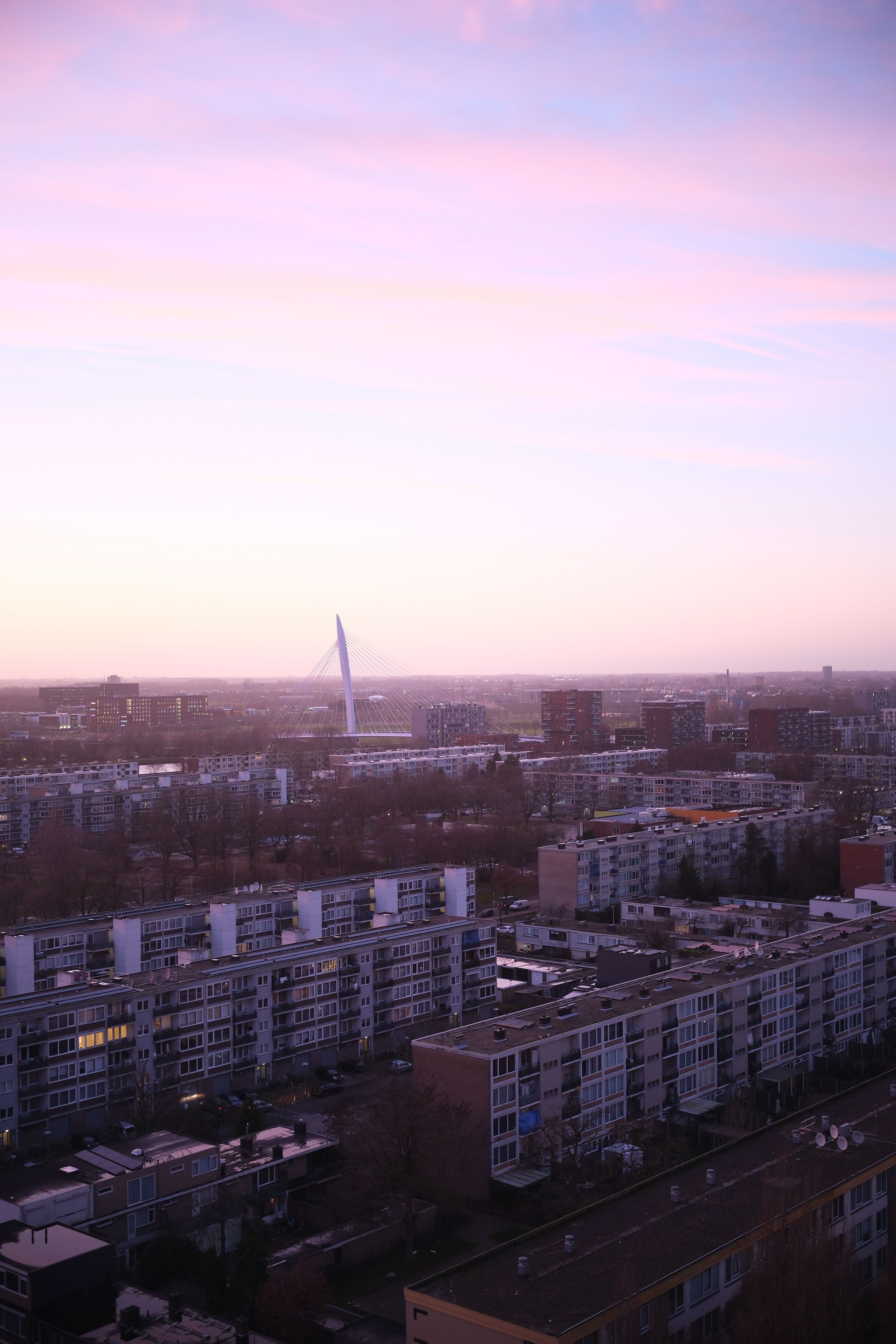 Aerial view of Utrecht city at sunset with iconic architecture under a pastel sky.