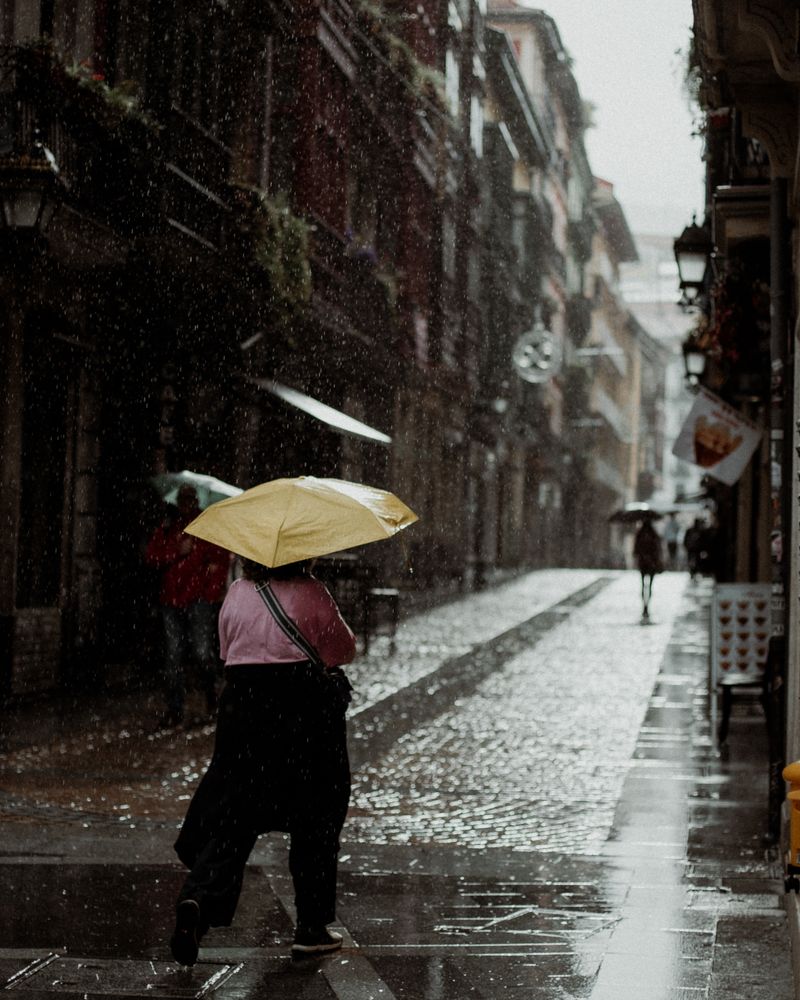 Rainy cobblestone street in a historic European city with wet pavement reflections