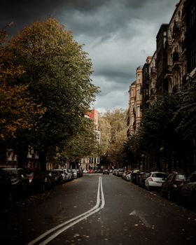 A moody urban street flanked by historic buildings under a dramatic sky.
