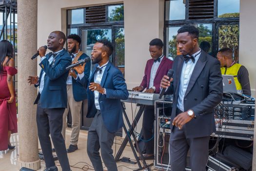 Group of musicians performing with microphones and keyboards at an outdoor event.