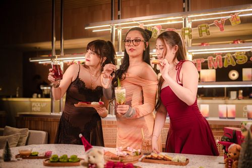 Free Three women enjoy a festive Christmas party indoors with drinks and treats. Stock Photo
