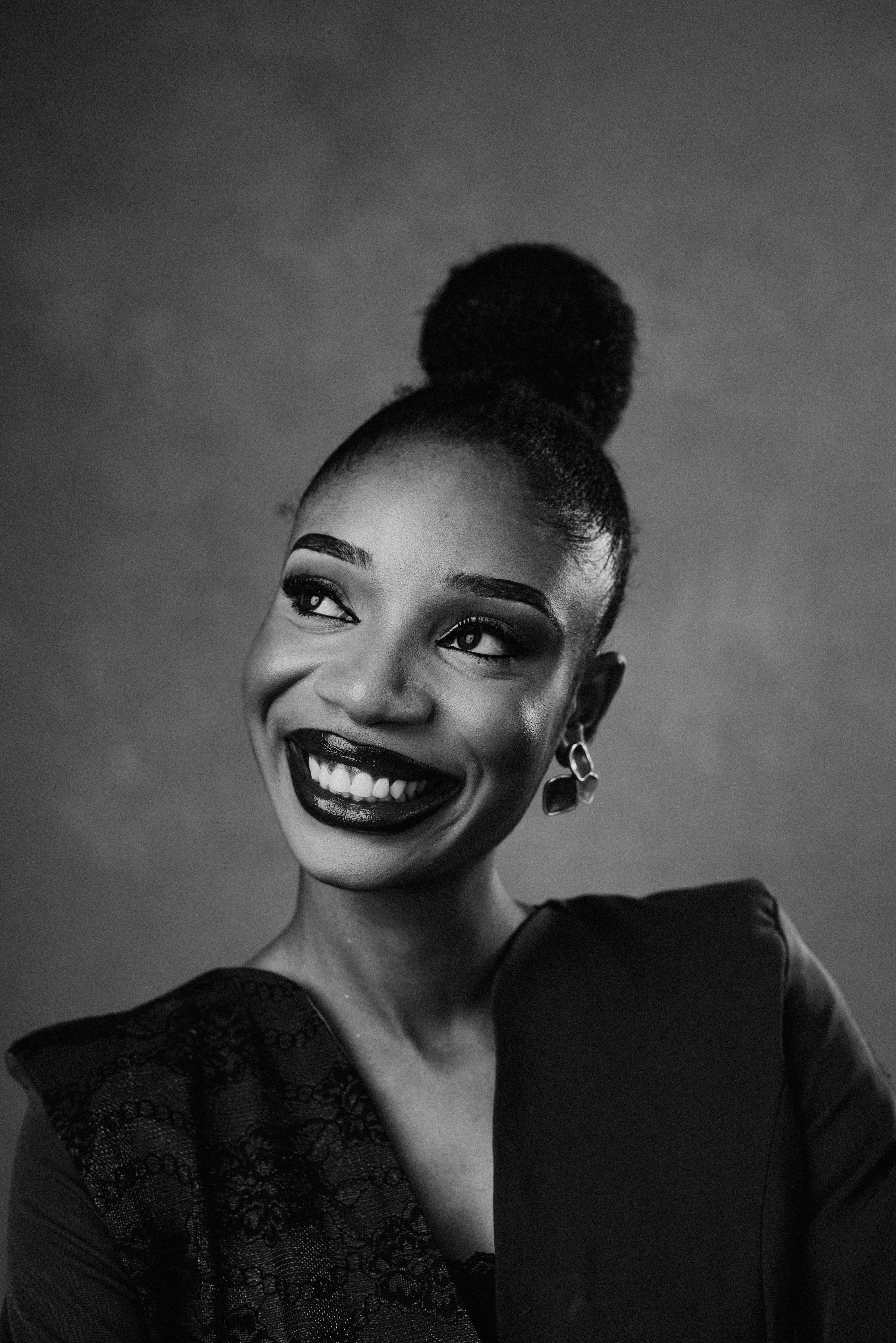 Kostenlos Elegantes Schwarz-Weiß-Porträt einer lächelnden Frau mit Duttfrisur. Stock-Foto