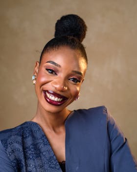 Elegant portrait of a smiling woman in formal attire with a neutral background.