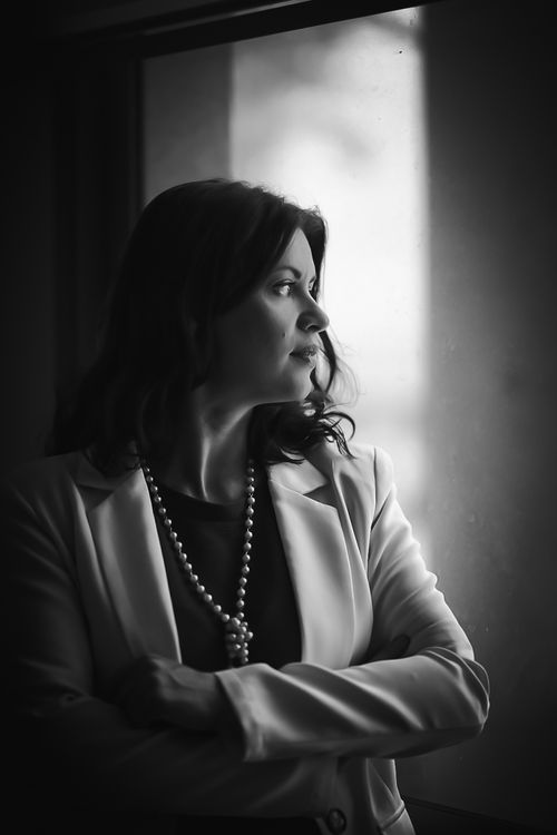 Free Black and white portrait of an elegant woman looking contemplatively out a window. Stock Photo