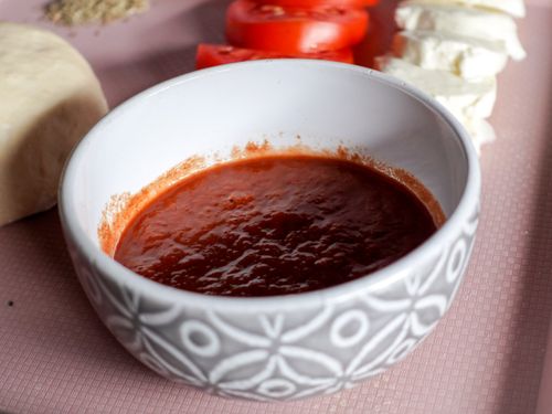 Free A bowl of tomato sauce surrounded by mozzarella cheese and sliced tomatoes, perfect for Italian cooking. Stock Photo