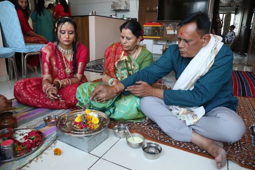 Free A family performing a traditional Hindu pooja ceremony with vibrant attire indoors. Stock Photo