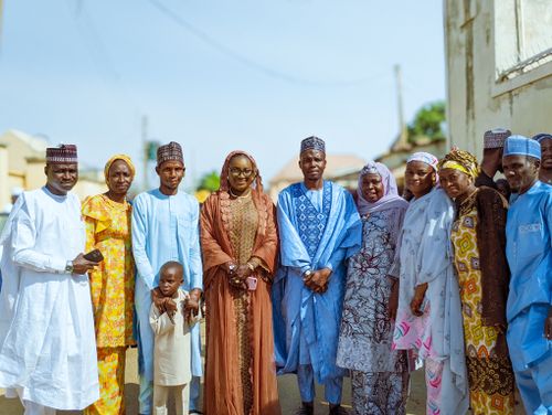 Free A joyful group of adults and a child in colorful traditional Hausa attire enjoying an outdoor gathering. Stock Photo