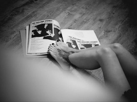 A person reading vintage Rolling Stones magazines on the floor, showcasing a relaxed vibe.