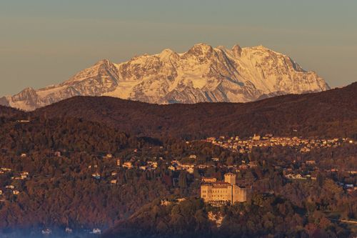 Free Stunning landscape of snowy Alps with a picturesque castle and forested hills during sunset. Stock Photo