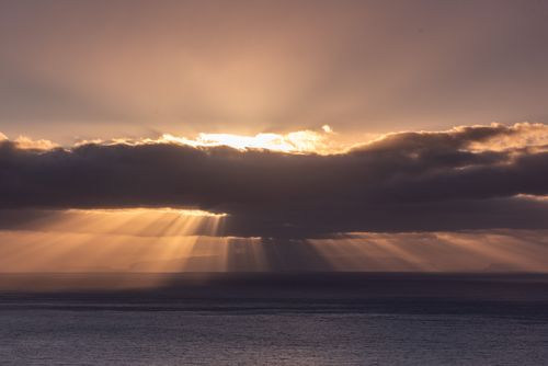 Free Stunning sunrise with sun rays breaking through clouds over the Atlantic near Funchal, Madeira. Stock Photo