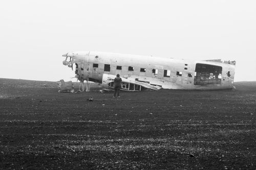 Free A lone figure stands by the abandoned DC-3 plane wreck on the black sand beach in Iceland. Stock Photo