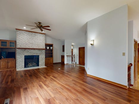 Bright and spacious living room featuring a brick fireplace, hardwood floors, and built-in cabinets.