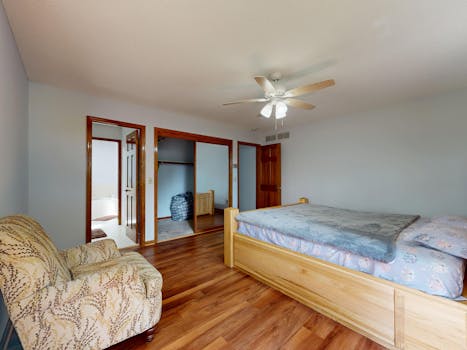 Bright bedroom interior with wooden furniture and ceiling fan.