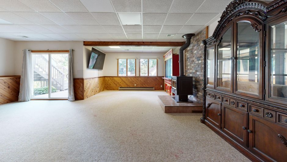 Cozy basement with wooden paneling, fireplace, and sunny windows. Great for relaxation.