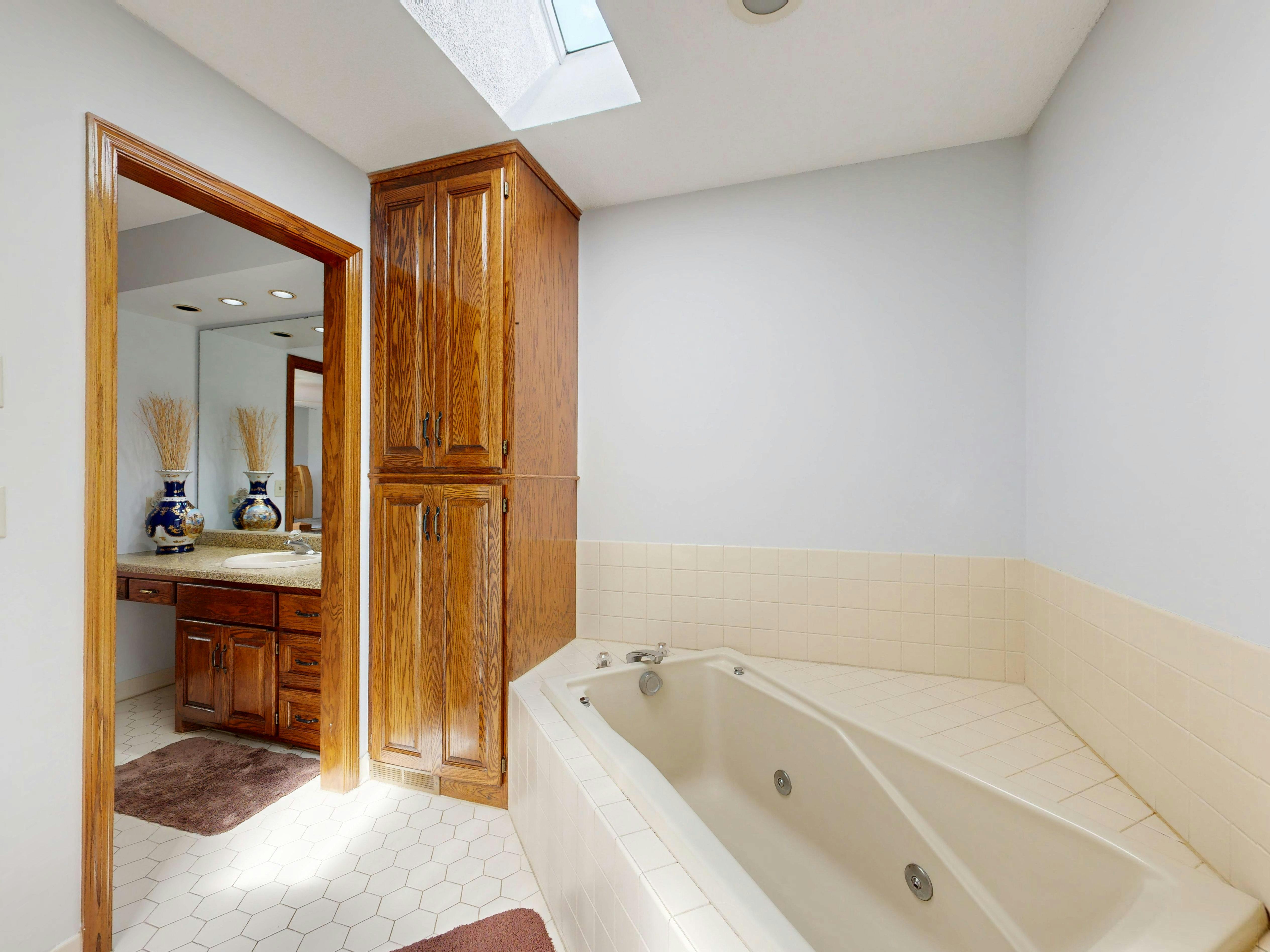 A contemporary bathroom featuring a jacuzzi and skylight, offering a luxurious and serene atmosphere.
