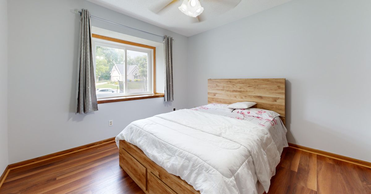 Comfortable minimalist bedroom with wooden bed and bright window view.