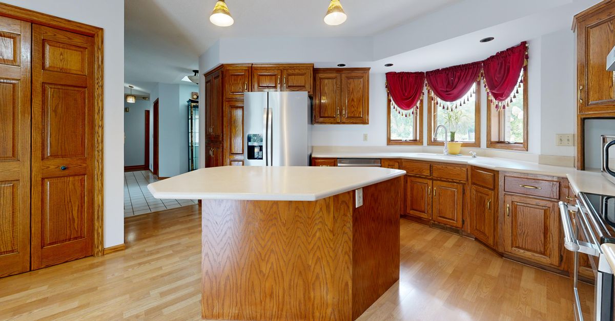 Traditional kitchen with oak cabinets, wooden island, and stainless steel refrigerator.