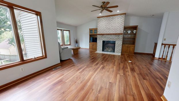 Bright living room featuring wood floors and a brick fireplace.