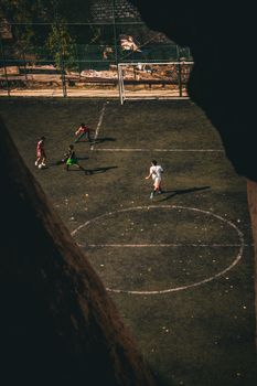 High-angle shot of a soccer match with four players on a city field.