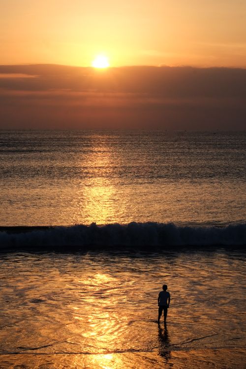 Free A lone figure on the beach at sunset in Bali, Indonesia, capturing tranquility and beauty. Stock Photo