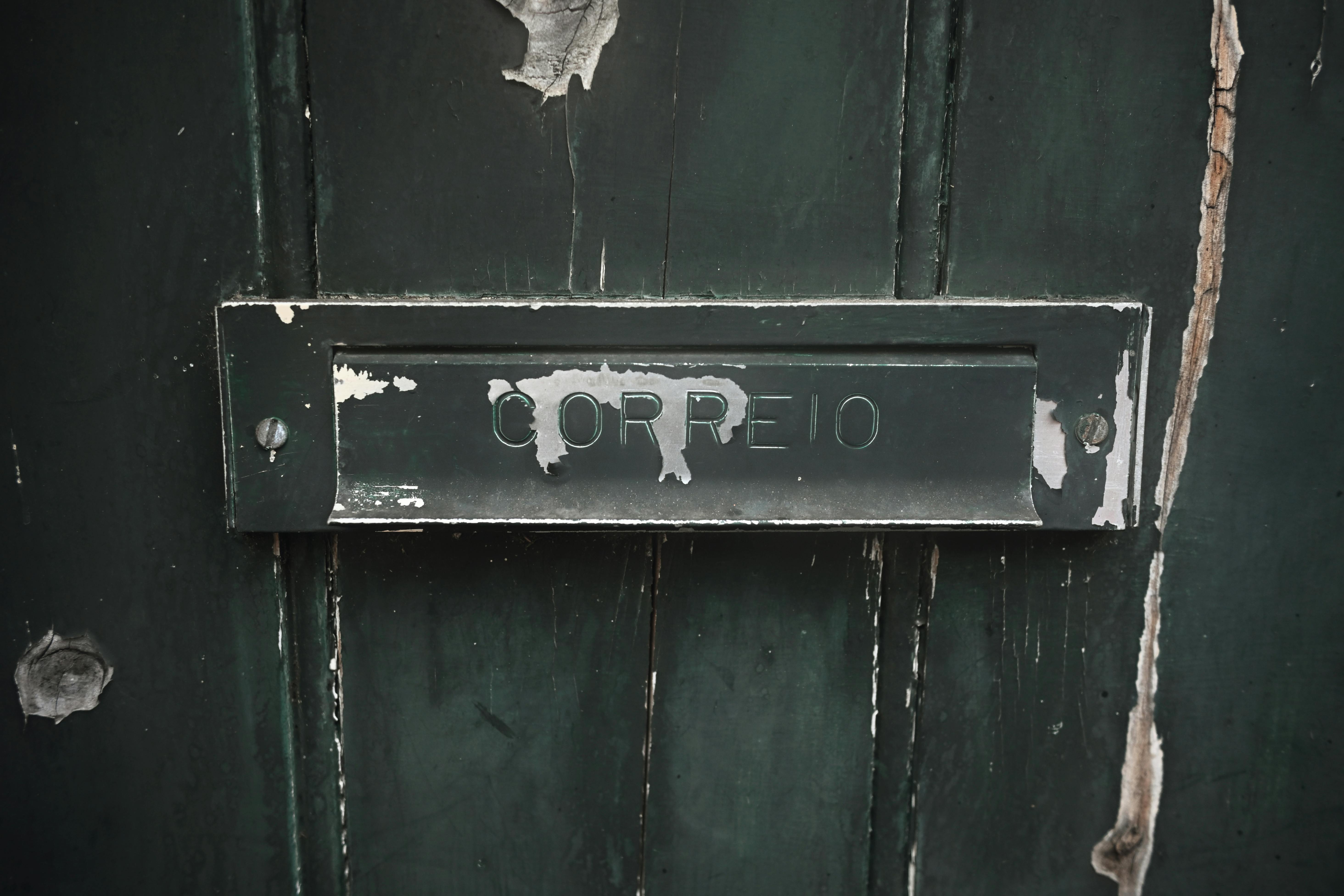 Gratis Un primer plano de una antigua ranura de correo con la etiqueta 'CORREIO' en una puerta de madera verde desgastada. Foto de stock