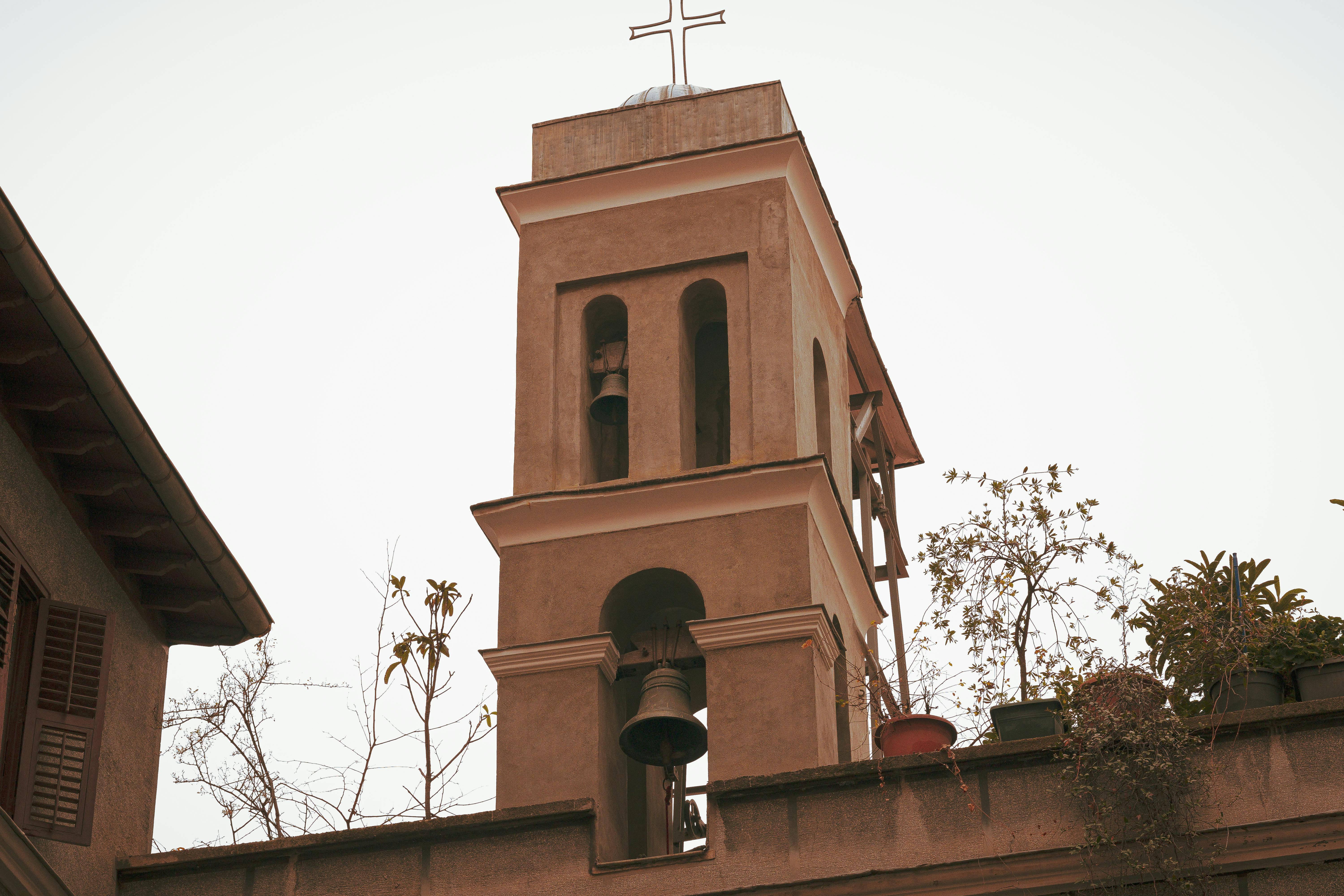 Rustic church bell tower with cross in Istanbul's Galata district, captured on a clear day.