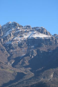 A stunning view of snow-capped mountain peaks under a clear blue sky in Lecco, Lombardy, Italy.