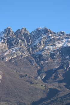 Majestic snow-covered peaks of the Italian Alps under a clear blue sky.