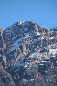 Stunning view of snow-capped mountains in Lecco, Lombardy, Italy, under a clear blue sky.