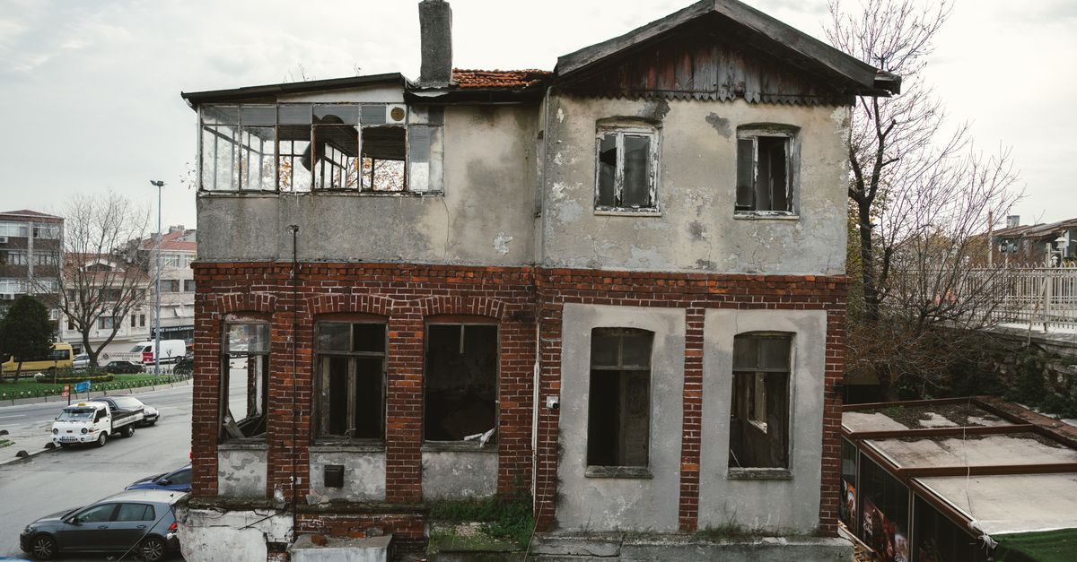 Verfallendes Wohngebäude mit rissiger Ziegelfassade und beschädigten Fenstern als Sinnbild für Sanierungsstau