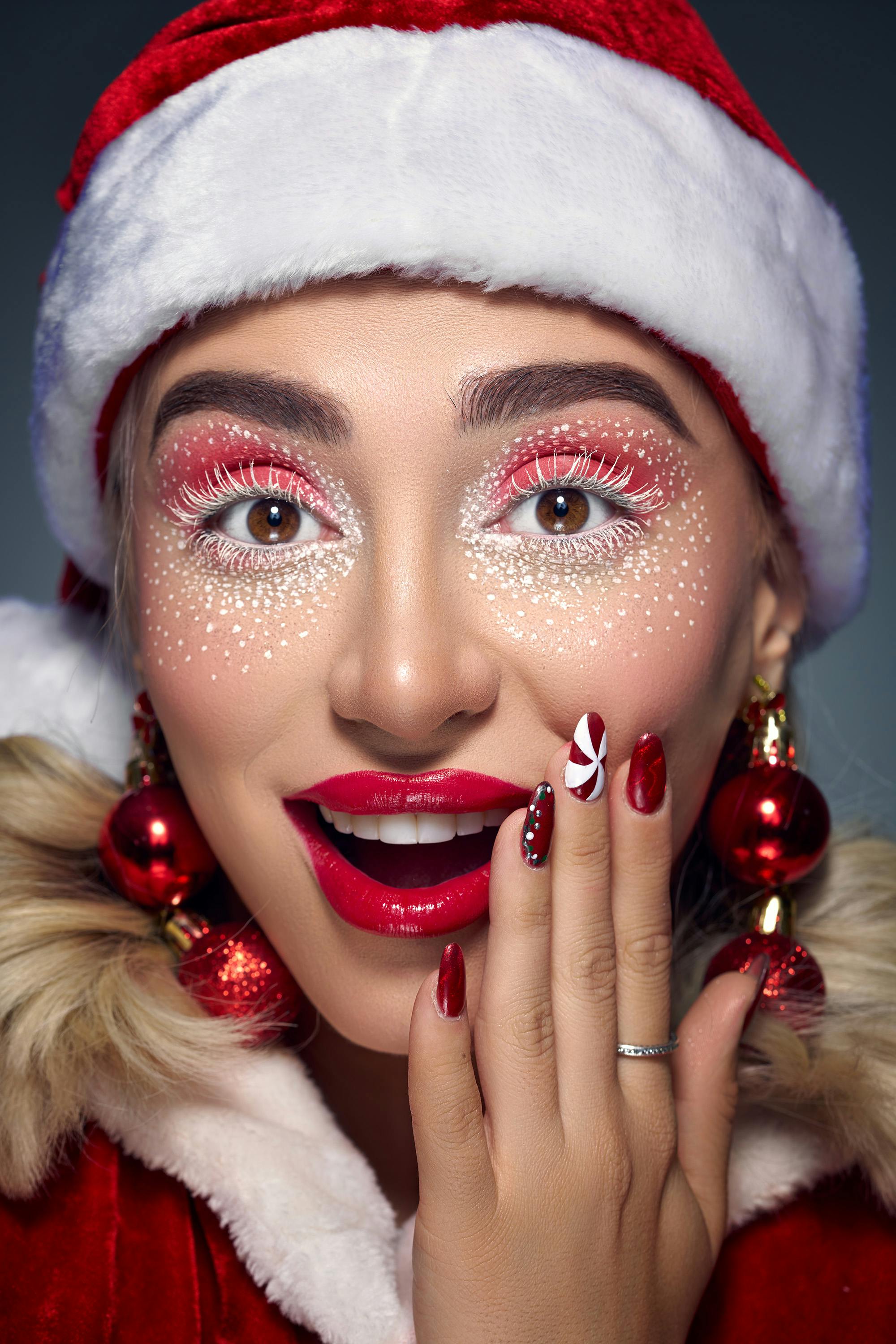 Gratis Retrato vibrante de una mujer con maquillaje festivo, uñas rojas y accesorios navideños. Foto de stock