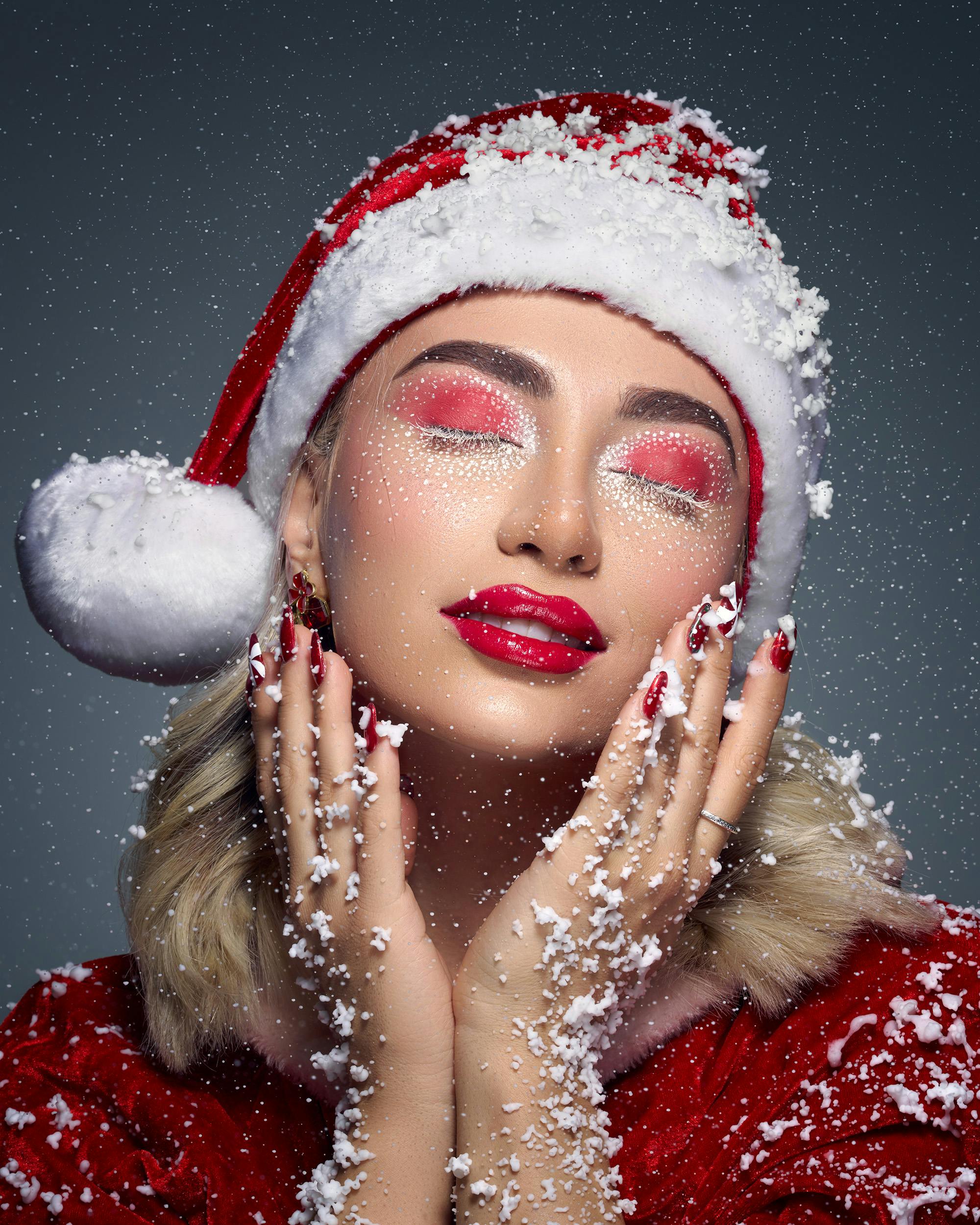 Gratis Elegante retrato de una mujer con atuendo navideño, maquillaje rojo, uñas y copos de nieve. Foto de stock