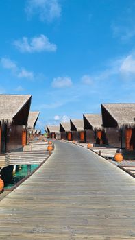 A serene view of tropical overwater villas under a bright, clear sky.