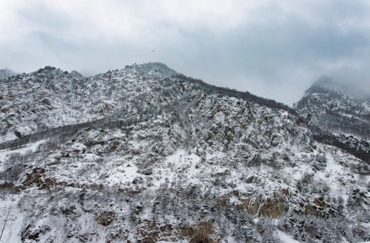 A breathtaking view of a snow-covered mountain range under a cloudy sky in winter.