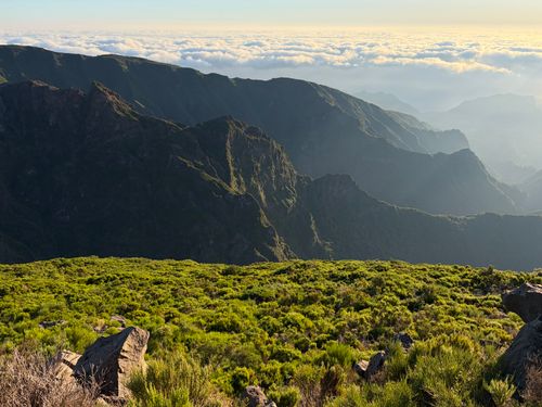 Free Stunning landscape showcasing a lush green foreground with towering mountains under a cloud-filled sky. Stock Photo