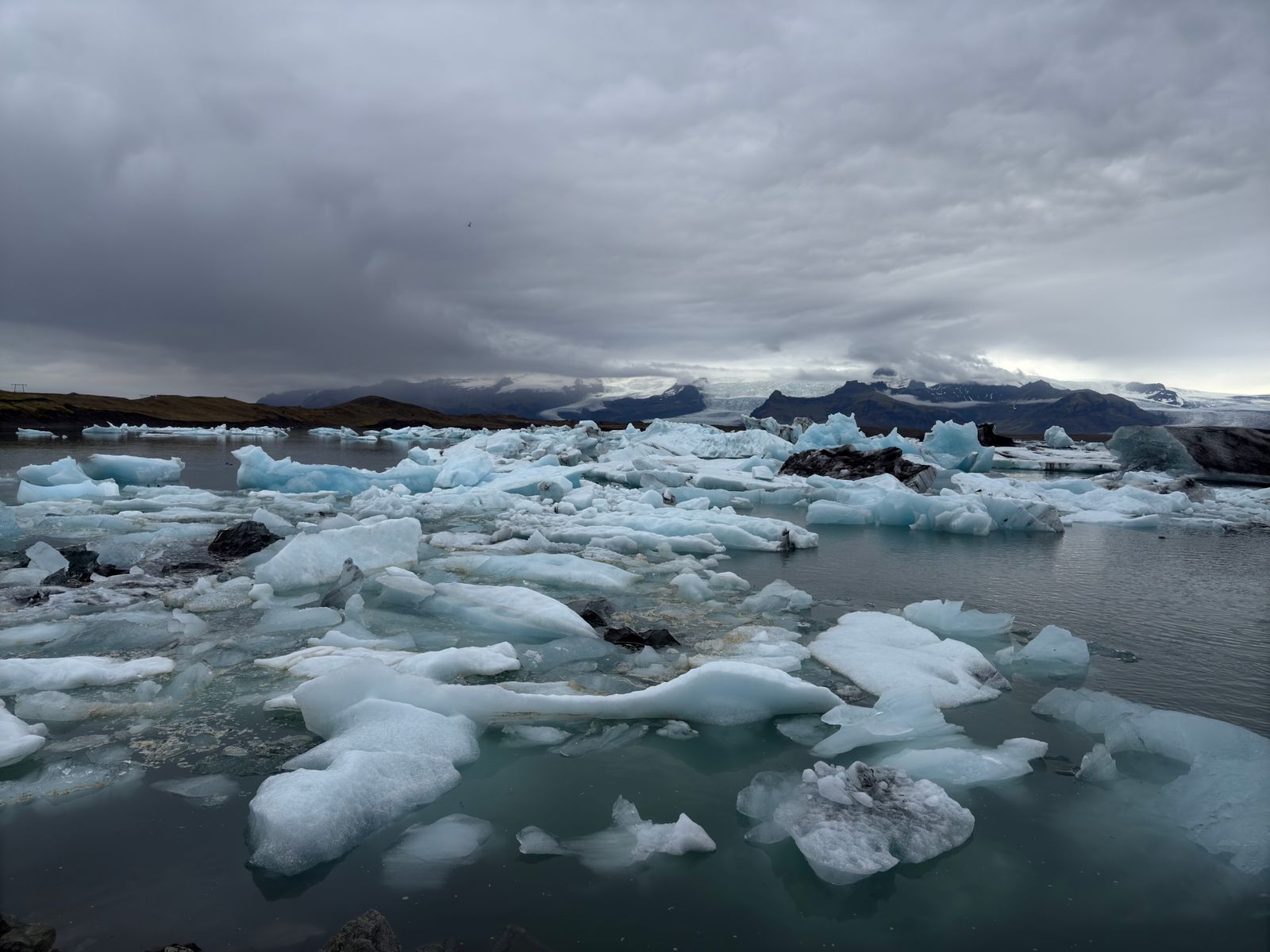Icebergs floating on the Jökulsárlón glacier lagoon under a dark, cloudy sky