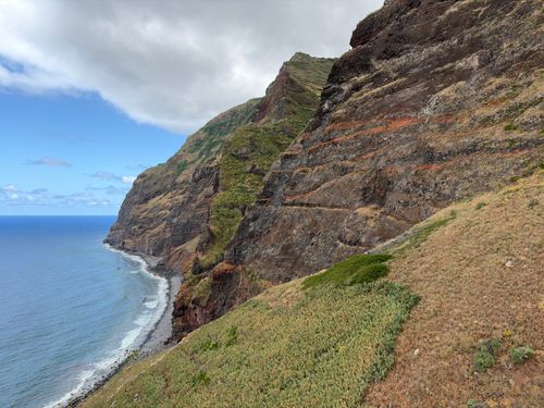 Free Stunning aerial view of rugged coastal cliffs against the blue ocean and cloudy sky. Stock Photo