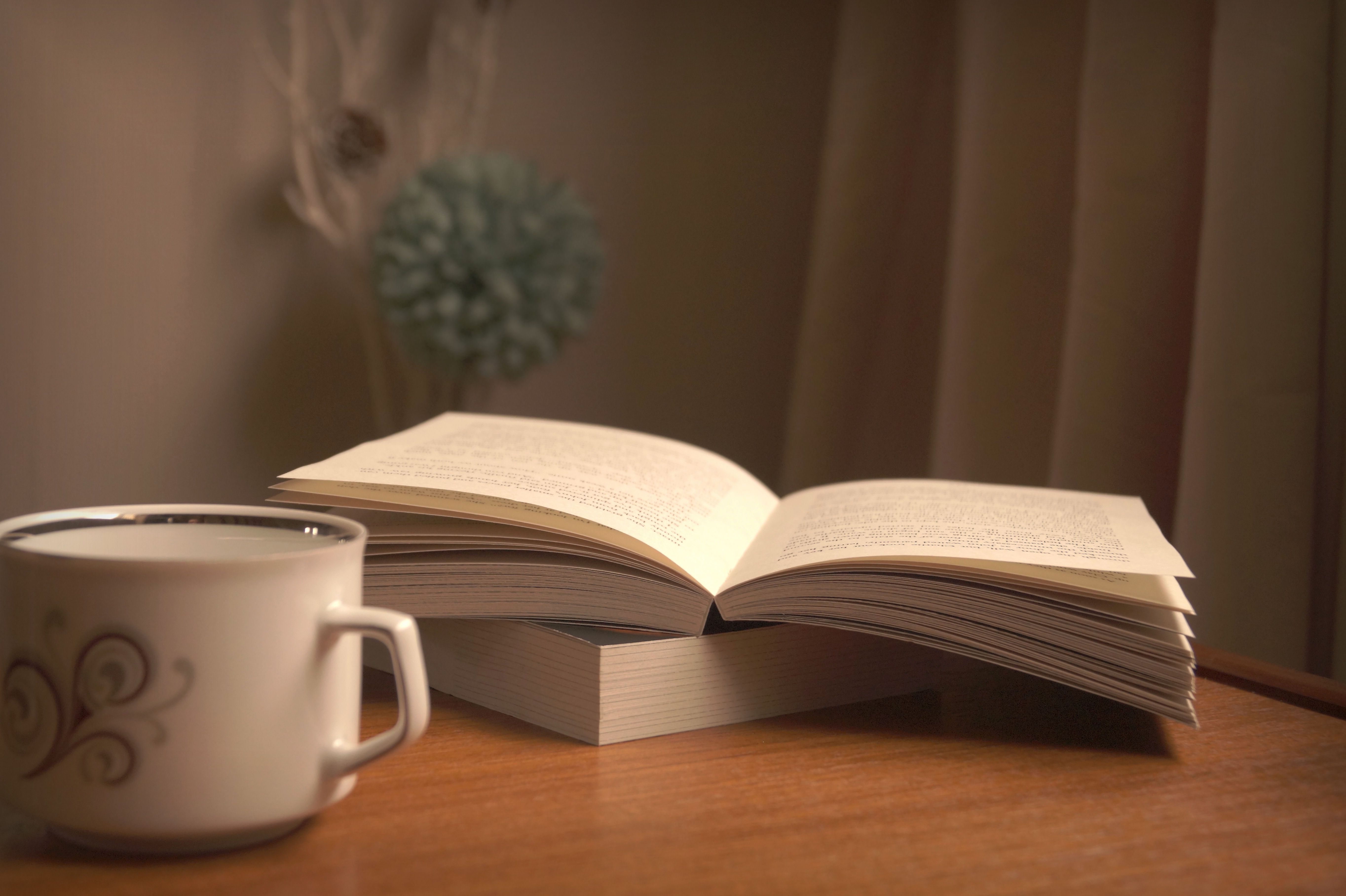 Open Bible with soft lighting and a cup of coffee on a wooden table