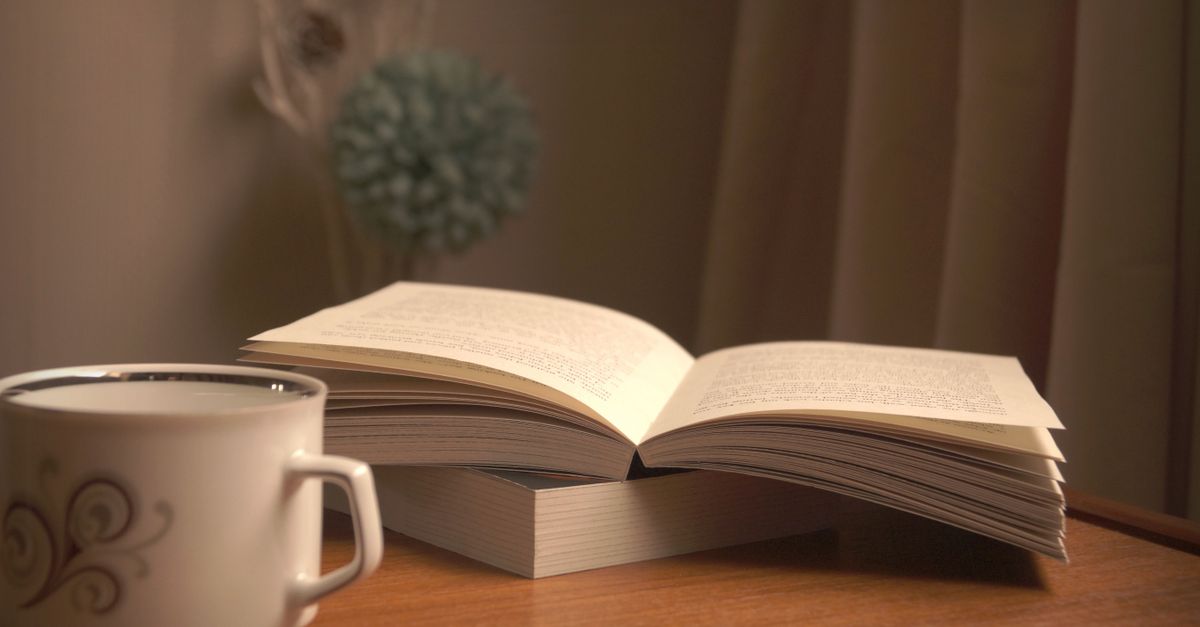 Open Bible with soft lighting and a cup of coffee on a wooden table