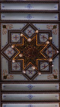 Detailed view of an intricate ceiling with a vintage chandelier, displaying rich patterns and colors.