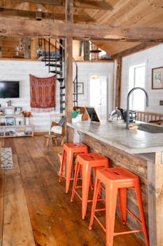 Charming rustic kitchen with red stools and wooden decor, ideal for a cozy countryside vibe.
