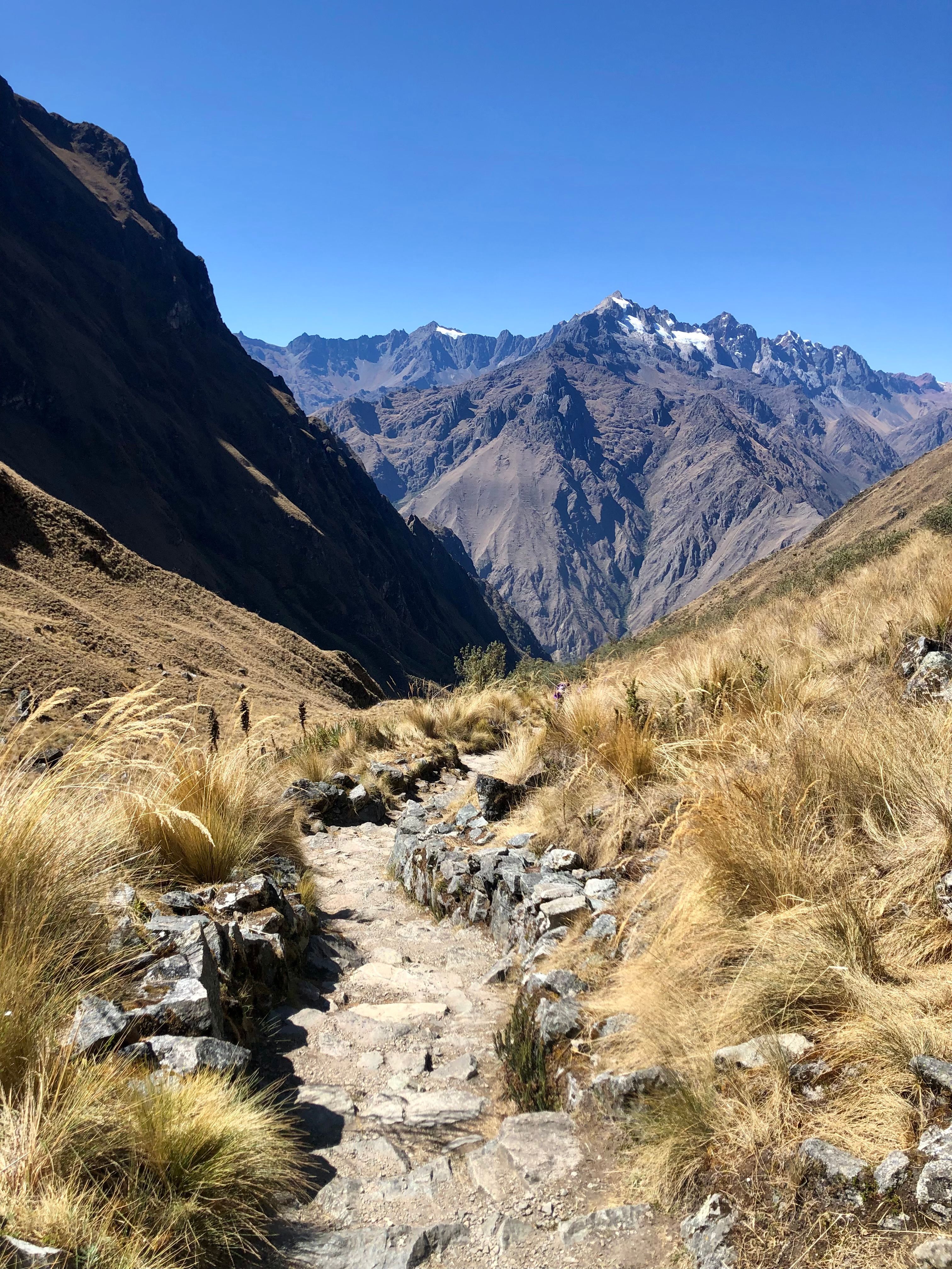 Photo of a rocky trail with mountain peaks in the background